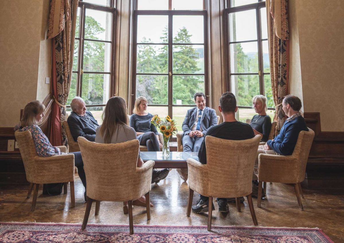 Group of men and women sat on beige chairs in a circle
