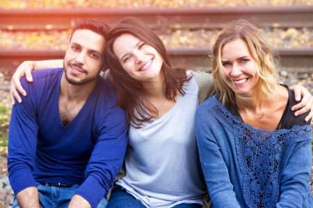 portrait of three friends sitting on train tracks and enjoying the sun