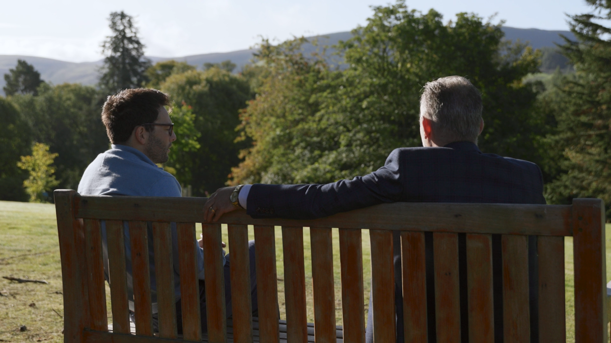 Male therapist talking to male patient outdoors.