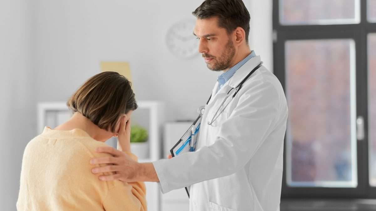 male doctor with clipboard comforting sad woman patient having health problem at hospital