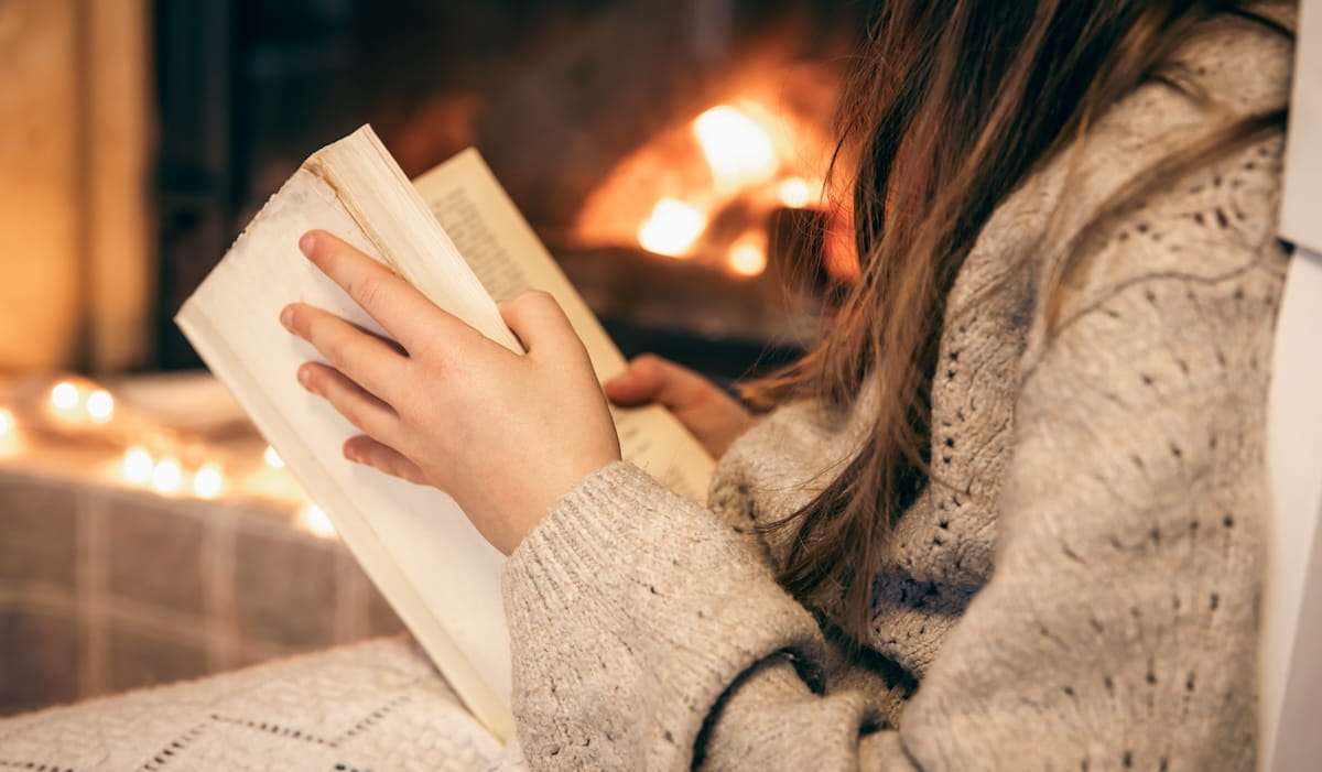 Reading bible sitting by the fireplace