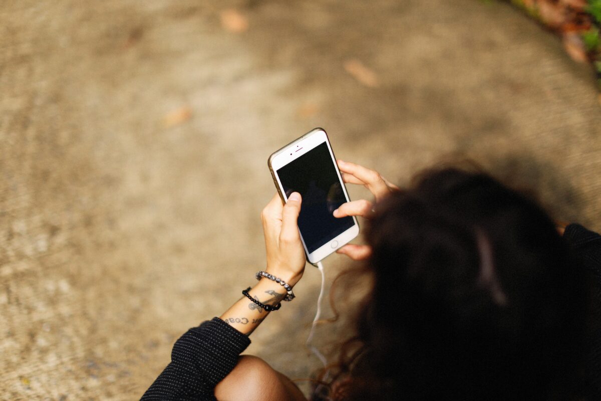 Yong adult with phone addiction, looking down at their iPhone with a blank screen